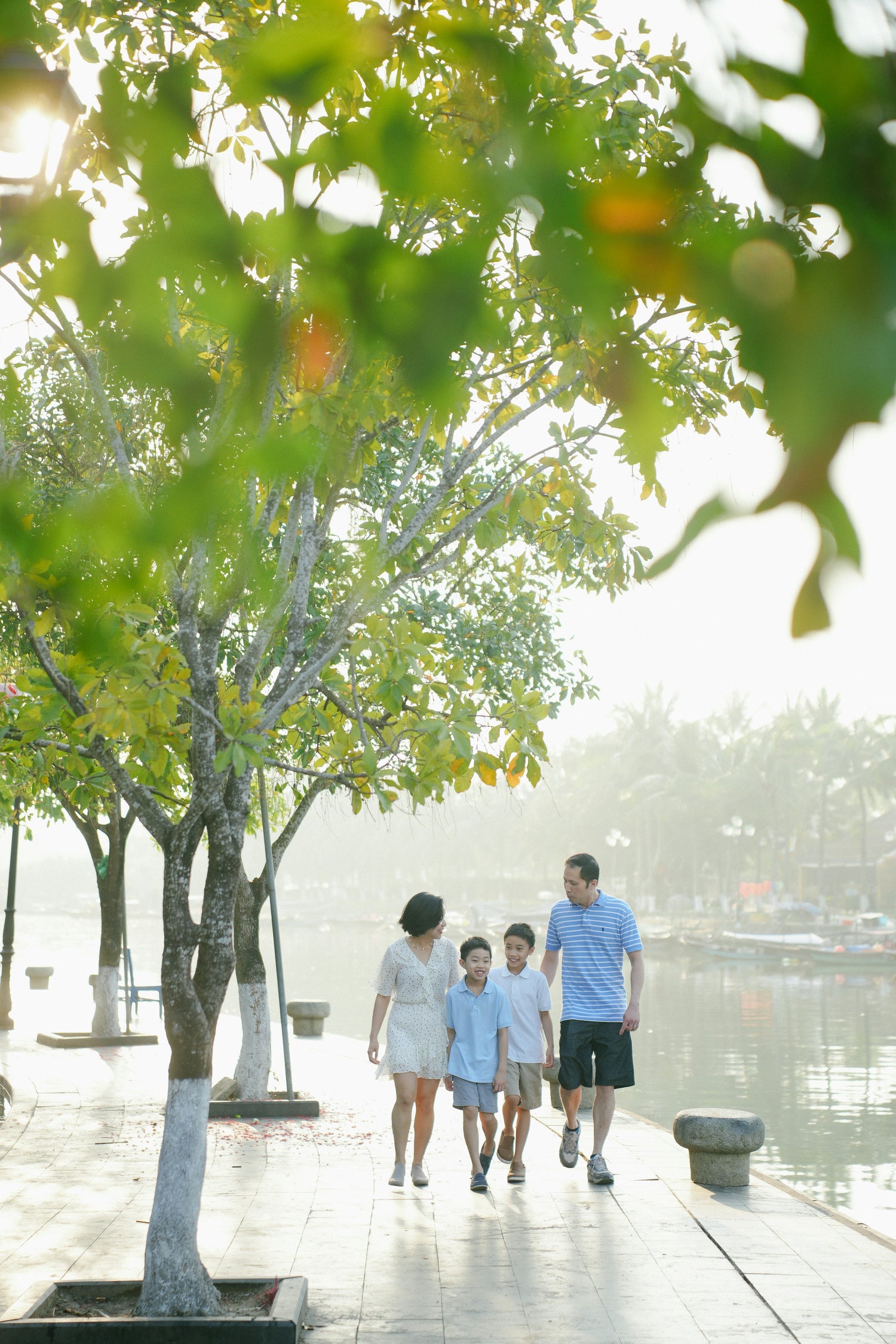 Family walking along a path by a lake with trees in the foreground